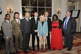 Six cast members and the series' creators dressed formally and posing at the awards hall