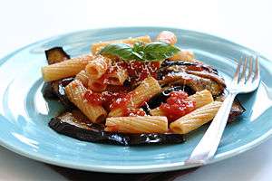 A plate of pasta with tomatoes, eggplant, basil, and cheese