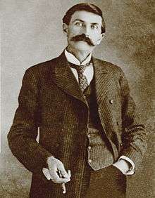 upper body of slender man in old-fashioned suit, vest and tie with short hair and large moustache