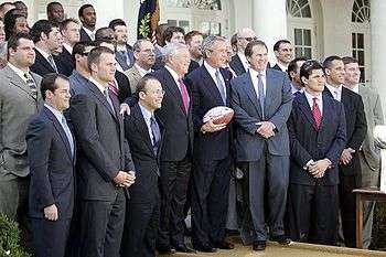 A large group of men standing together, including George Bush and Robert Kraft in the middle.