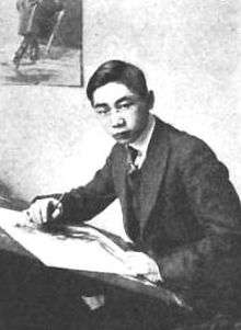 Black-and-white photograph of a man posed at a drawing board