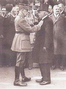 Michaux being presented the Legion of Honour. Michaux is dressed in dark colours and Foch in lighter colours
