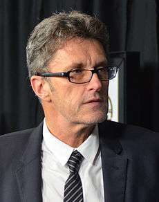 Bespectacled man in a grey suit. This is a photo of Paweł Pawlikowski in 2015.