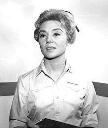 A woman with blond hair, wearing button shirt.