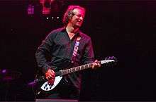 Peter Buck playing guitar and smiling