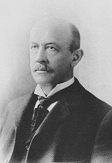 Sepia-toned, half-length photographic portrait of William Graham Sumner in a three-piece suit