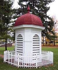 the red-roofed white cupola from the 1927 building, surrounded by a small white picket fence