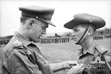 B/W Photo of a gentleman pinning the Military Cross on Harry Smith in military uniform, 1967