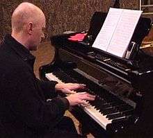 Middle-aged man in black, playing grand piano