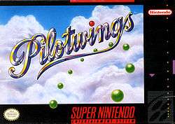 The image shows a cursive title "Pilotwings" in front of a cumulus cloud-covered sky and a ring made of green orbs visible on the bottom right. The artwork has a black border with various labels on it.
