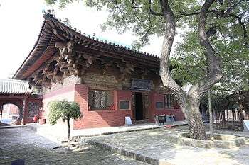 The Wanfo Hall of Zhenguo Temple. The tiled roof is decorated with small, ornate dragons. There is one door opening to a bricked courtyard