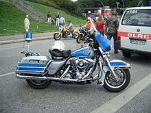 A Harley-Davidson motorbike in blue and silver, with a helmet on the seat.