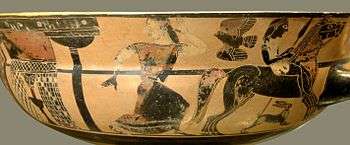 One side of a painted bowl. A mounted youth holding a spear rides away from a fountain. A woman runs after him. She is looking back towards the fountain.