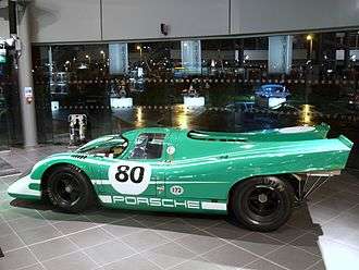 A picture of a green racing sports car from the side in an indoor setting
