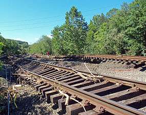 Two sets of railroad tracks twisted and tilted, with some woody debris on and around them