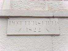 A white wall carries a stone plaque engraved with the word "Pottersfield" in upper case letters. Below this are the numerals "1822".