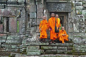 monks in orange robes on stone steps in Cambodia