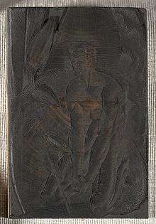 Photograph of an engraved piece of wood, on which is an image of a man kneeling.