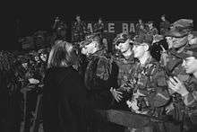 Clinton greeting U.S. troops at Tuzla Air Base in Bosnia while she is walking. This image was taken in December 1997.