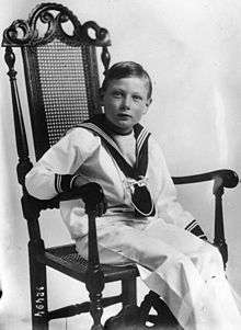 A picture of Prince John on a chair wearing a black glove.