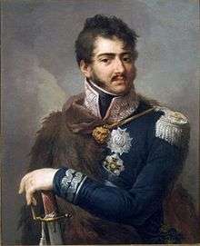 Color portrait of a man with dark brown hair, mutton chops and a moustache. He wears a dark blue uniform with silver braid and a fur cape over his right side.