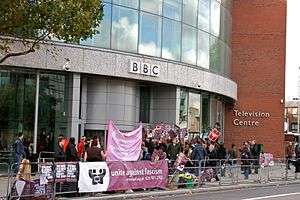 Banner-waving protesters in front of a building with BBC logo