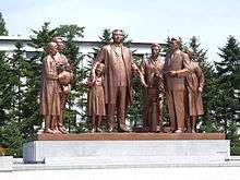 A Bronze statue of Kim Il-sung and six other people with a camera, a flower basket and a notebook.