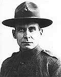 Head and shoulders of a stern-faced white man wearing a plain military jacket and campaign hat.