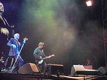 R.E.M. performing onstage, with Michael Stipe singing, Peter Buck playing guitar, and Scott McCaughey playing keyboards