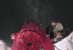 The bottom of a telescope in the foreground, with the night sky above.