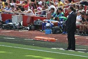 A coloured photograph of manager Rafael Benítez standing on the stadium touchline.