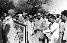 A black-and-whitу photo of Rajiv Gandhi holding a book and surrounded by Russian Hare Krishnas