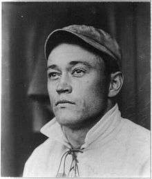 An old picture of a man wearing a baseball cap looking to the photographer's left.