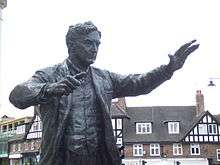 Outdoor statue of middle-aged man with raised arms as if conducting an orchestra