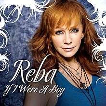 A woman is standing in front of a wall. She is wearing a blue blouse and four necklaces with crosses at the end. Her hair is red and she has blue eyes. The words "Reba" and "If I Were A Boy" are written in white capital letters upon her image.