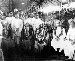 A group of people seated with garlands around the necks of some.