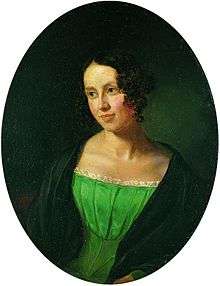 Portrait of a young lady, over a black background. She is wearing a green dress, over a black coat. She is looking to the left, somewhat smiling.
