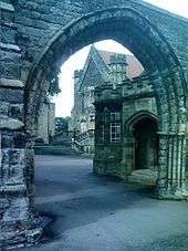 A school viewed through a stone gateway