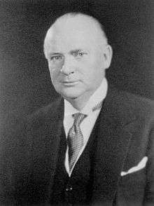 An older white man in a three piece suit, looking at the camera