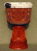 Djembe decorated with extensive carvings on the stem and bowl, with folded-over skin