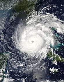 Satellite image of a strengthening hurricane passing between two landmasses. The hurricane has also developed an eye.
