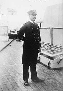 A standing man in naval uniform.