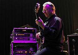 Robert Fripp ergonomically plays electric guitar while sitting in a posture developed through years of application of the Alexander Technique.