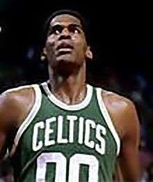 A man, wearing a green jersey with a word "CELTICS" and the number "00" written in the front, is looking up.