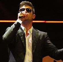 Robin Thicke wearing sunglasses and holding a microphone.