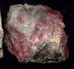 A rough chunk of rhodonite showing white and intense pink crystals.