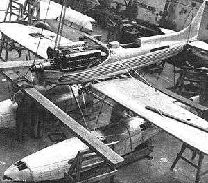 A single-engined floatplane is being built in a hangar, the engine covers are removed.
