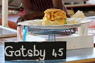 A personal-sized Gatsby sandwich prepared with calamari and chips, being sold at a food stall