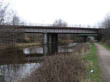 Flat steel bridge crossing waterway with towpath to right