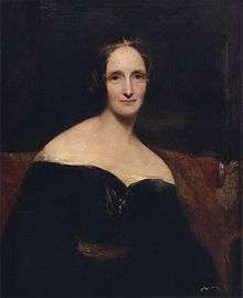 Half-length painted portrait of a woman wearing a black dress, sitting on a red sofa. Her dress is off the shoulder, exposing her shoulders. The brush strokes are broad.